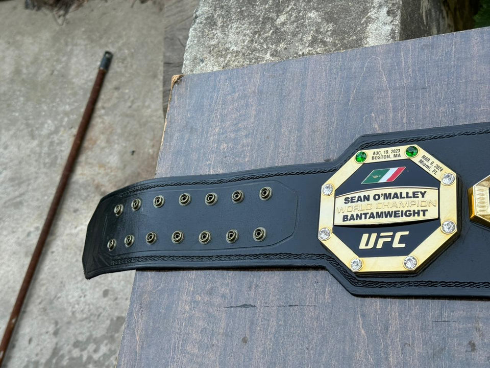 UFC World Champion (Octagon Design) replica belt, strap eyelets and name plate close-up