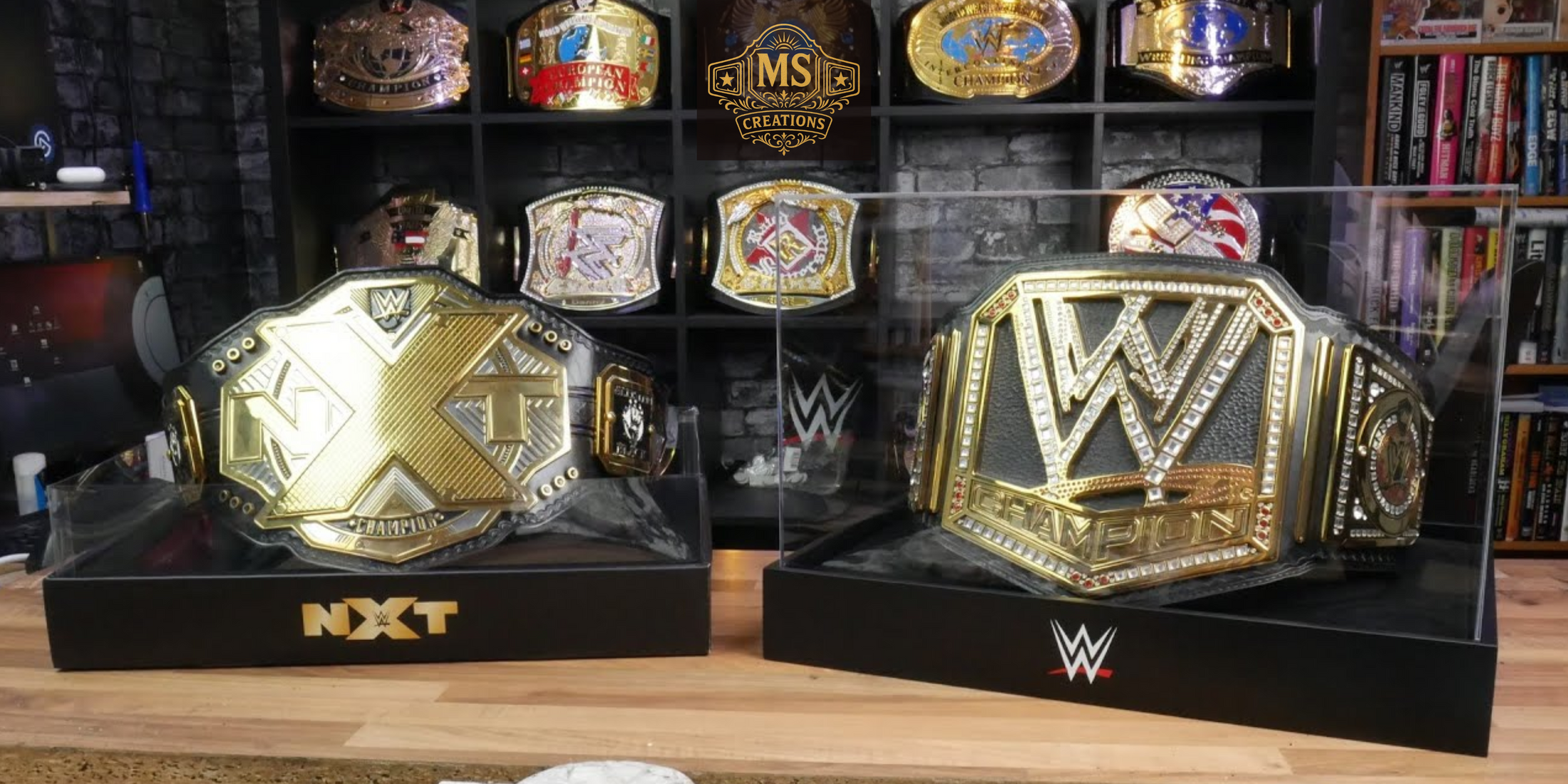 A championship belt display featuring the NXT Championship and WWE Championship belts, with several other championship belts on shelves in the background.